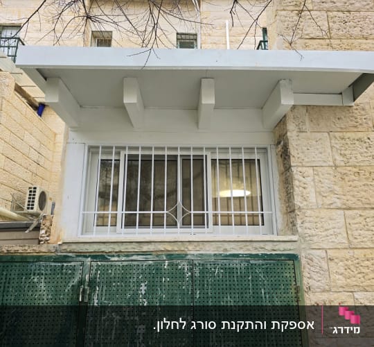 חלון עם סורגים ומסגרת מתכת ירוקה